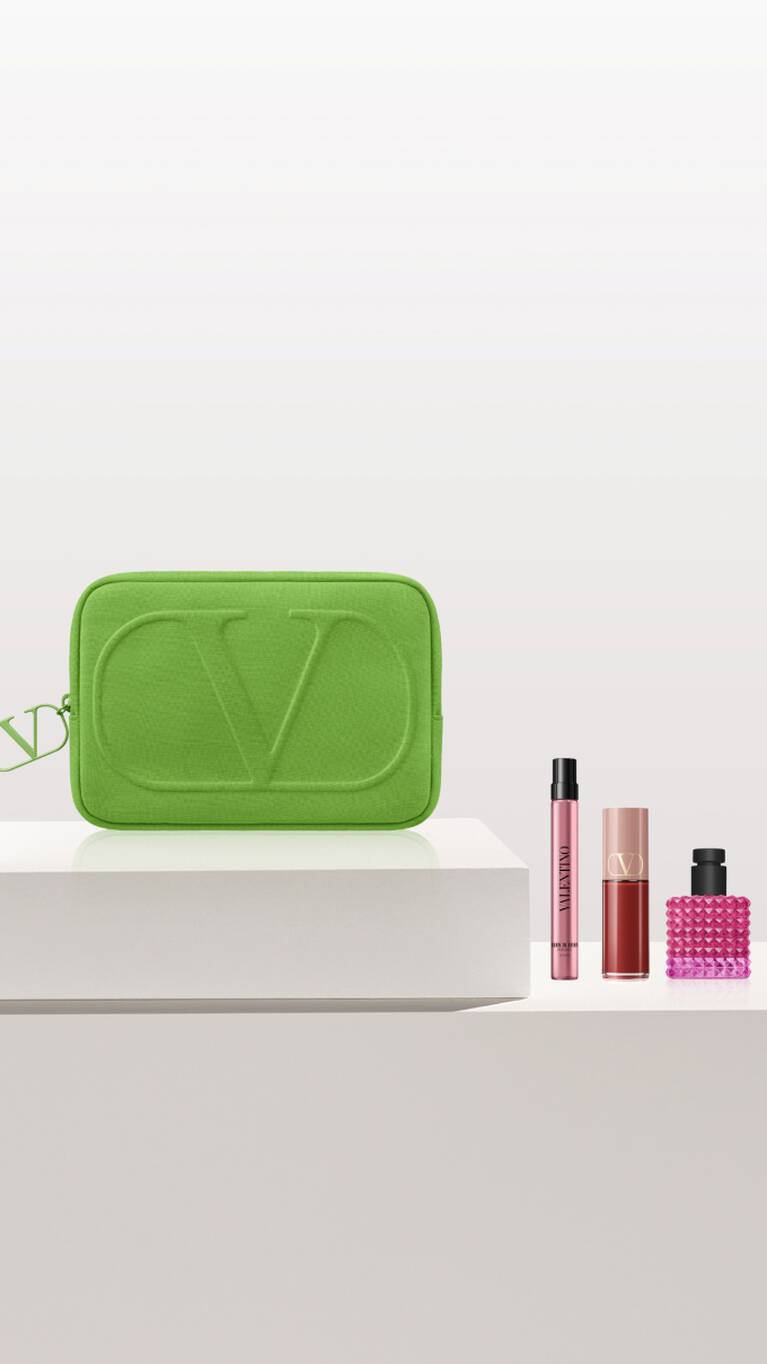 Trousse verte avec logo CV, accompagnee de flacons de parfum et de maquillage sur une surface claire.