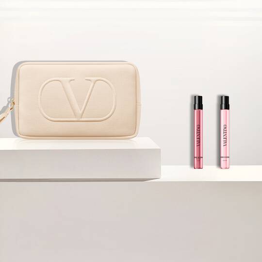 Pochette Valentino beige et deux echantillons de parfum Valentino Born In Roma Donna sur des socles blancs.