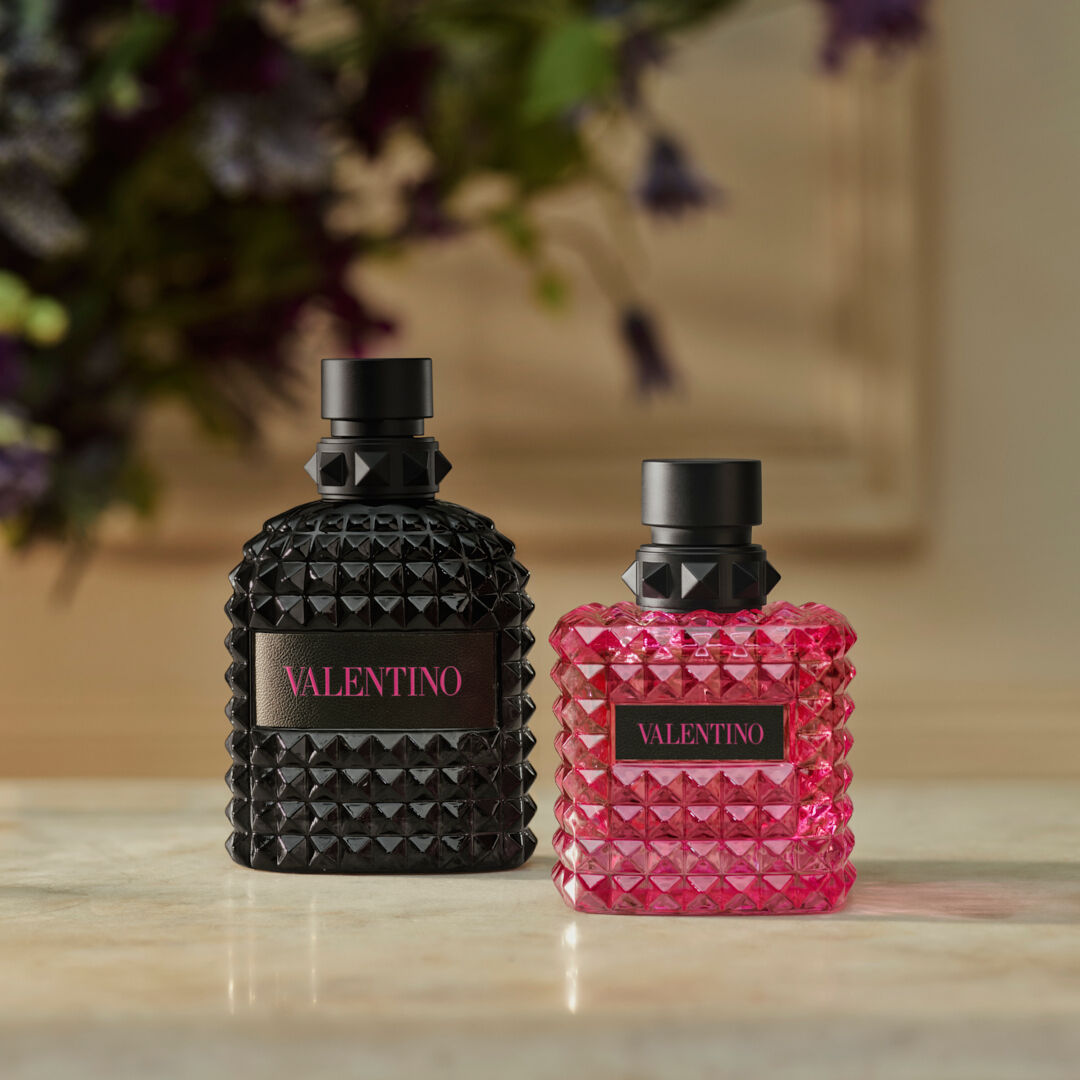Deux flacons de parfum Valentino, l'un rose et l'autre noir, poses sur un fond texture. Elegance et modernite.