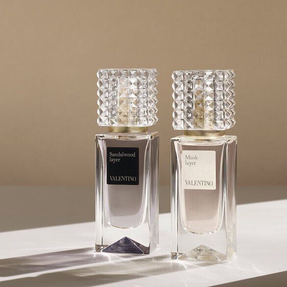 Deux flacons de parfum Valentino, nommes Sandalwood Layer et Musk Layer, presentes sur une surface claire