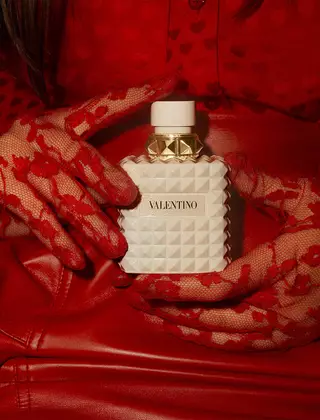 Une femme en rouge, portant des gants en dentelle rouge delicatement ornes, tient BORN IN ROMA IVORY DONNA.