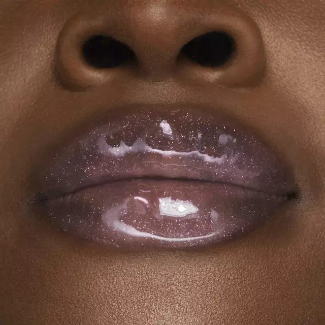 Gros plan sur des levres brillantes avec un gloss paillete, mettant en valeur une peau satinee.