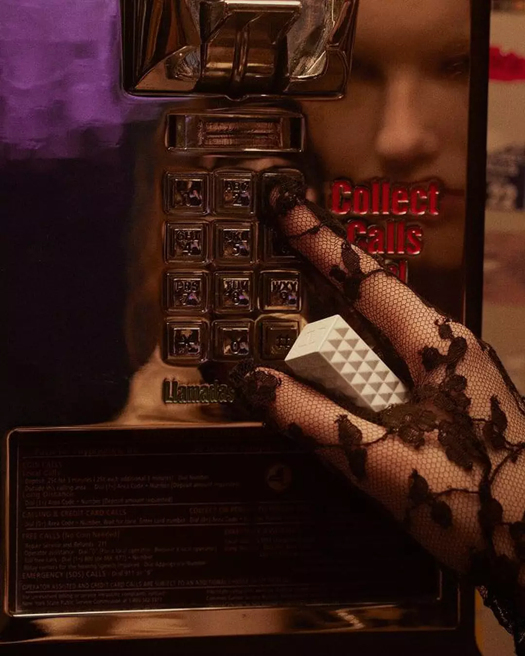 Une femme portant des gants en dentelle noire, tenant le SPIKE VALENTINO IVORY, appuie sur le clavier d un telephone vintage.
